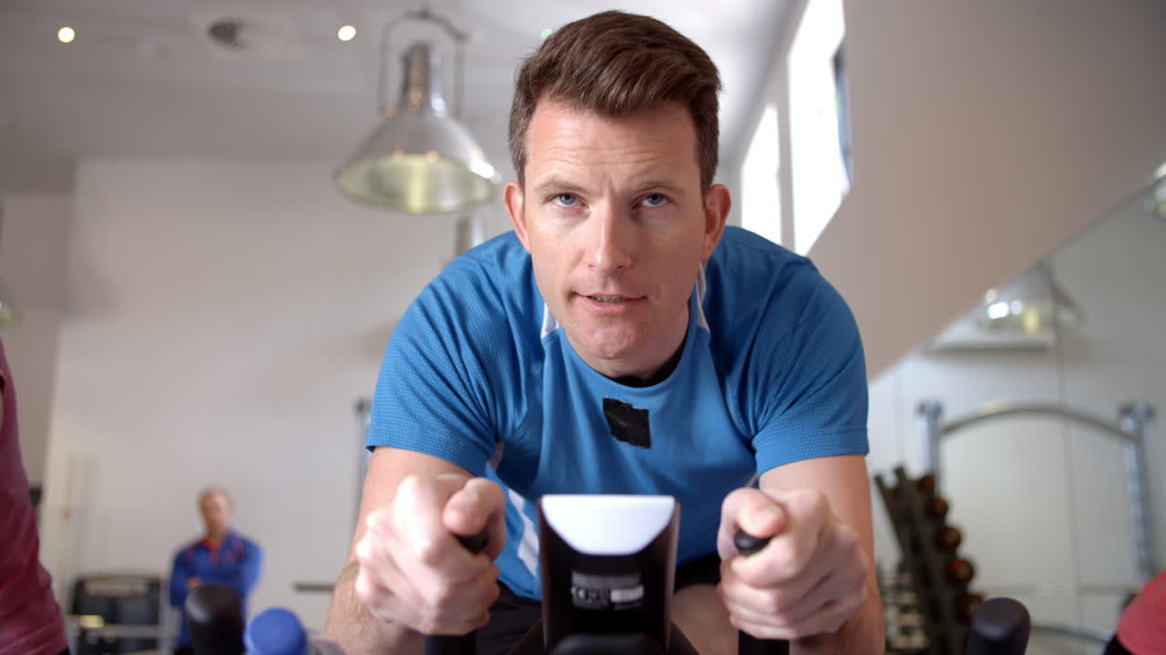 운동 자전거 를 타고 체육관 에서 스핀링 수업 을 하는 사람