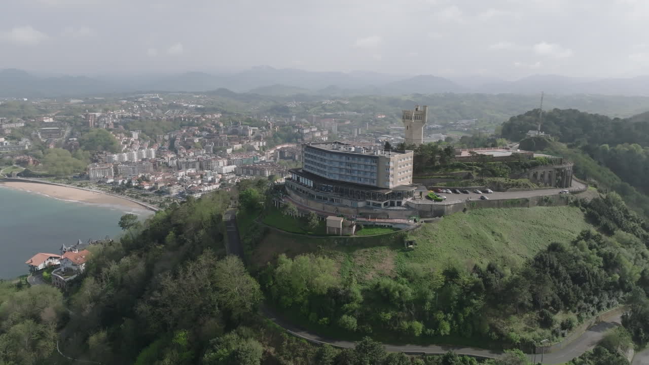 Drone aerial shot of San Sebastián (Spain) with La Concha Bay, the city skyline, and Monte Igueldo’s iconic tower. A scenic coastal view from above, perfect for travel and tourism themes
