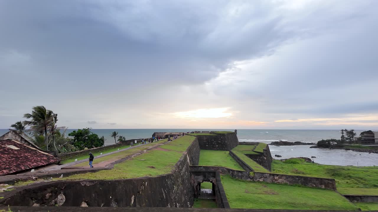 Tourists walking on the ramparts of galle dutch fort at sunset, a unesco world heritage site in sri lanka. pan left