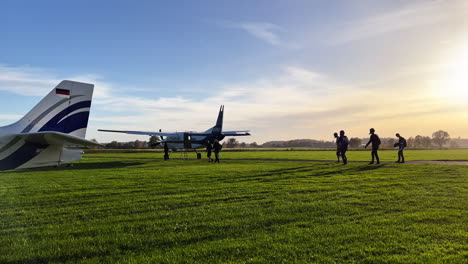 Weite-Einstellung-Von-Ein-Paar-Fallschirmspringern,-Die-Sich-Fertig-Machen-Und-Zum-Flugzeug-Am-Boden-Gehen