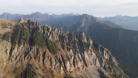 a high-flying, slow rotating drone shot, over mountain peaks of the rocky mountains, near telluride, colorado, on a sunny day in the fall season