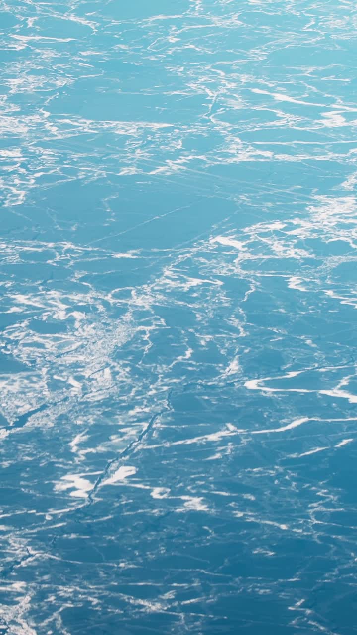 Vista aerea astratta di acqua blu ghiacciata con motivi di ghiaccio bianco, che cattura una fredda texture invernale dall'alto in una scena di viaggio minimalista
