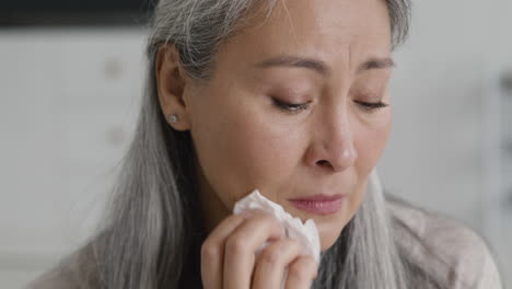 portrait of sad middle aged woman crying and drying her tears with tissue