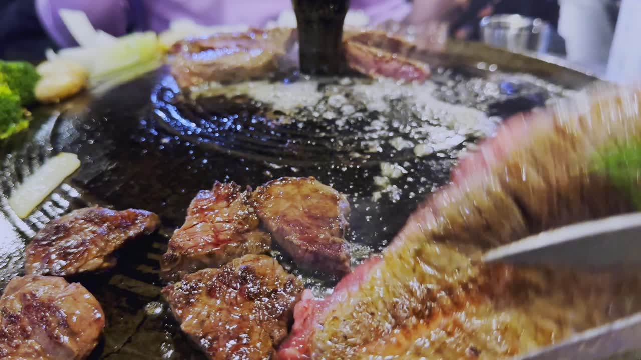 알아볼 수 없는 사람이 한국 그릴에서 요리하는 스테이크를 확인합니다.