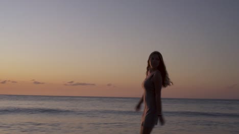 silhouette of carefree sexy girl running spinning on the beach at sunset