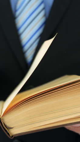 mid-section of businessman flipping pages of book