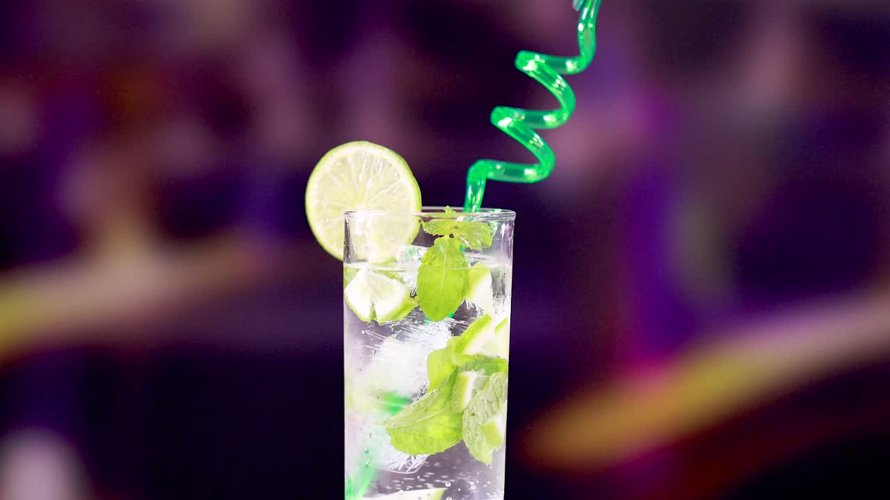 un refrescante cóctel de mojito con lima y menta, con una paja en espiral dinámica contra un fondo vibrante y colorido