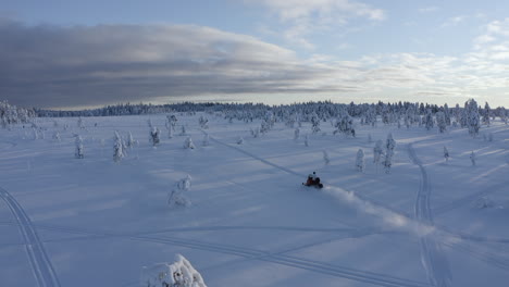 drone aerial shot following a snowmobiler on a track with speed in the nature of sweden