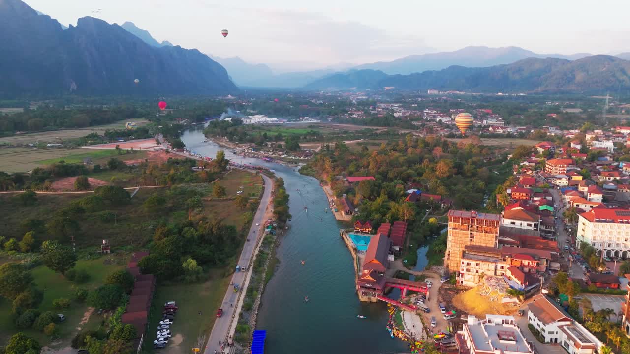 avión no tripulado volar vang vieng pequeña ciudad turística en laos al otro lado del río con globos de aire caliente en el cielo