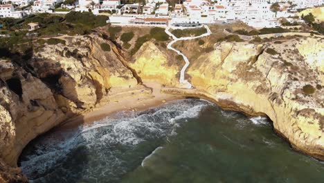 waves crashing into sandstone cliffs in carvoeiro, algarve, portugal