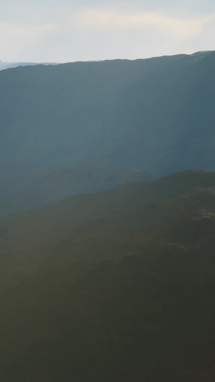paisaje de montaña con un cielo azul y una niebla brumosa