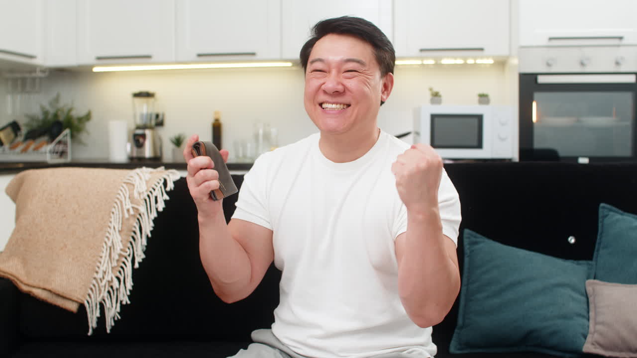 Asian man holds cash euros as fan laughs shows victory sign puts money into wallet after count win