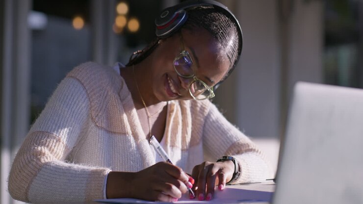Woman with Headphones Writing at Table