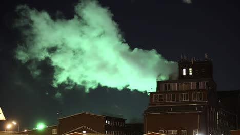 green smoke from chimney of night industrial cityscape with carbon emissions from factory