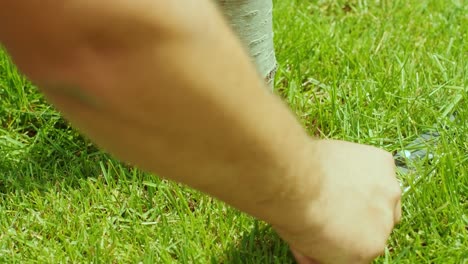 human hand using 2scissors to cutting grass cuts grass mows the lawn near the tree