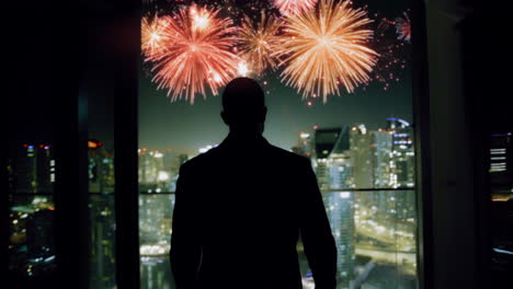 hombre de negocios viendo fuegos artificiales sobre la ciudad por la noche