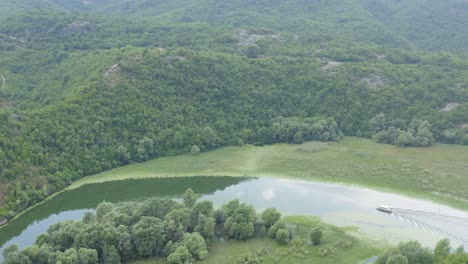 Sunset-over-Skadar-Lake-in-Montenegro-with-boat-between-rolling-green-hills,-aerial