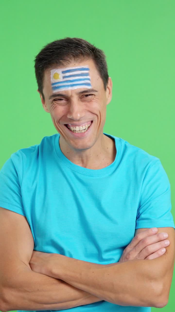 Man standing with uruguayan flag painted on face smiling