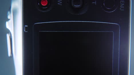 a macro close up shot of a video camera, silver camcorder on a 360 rotating stand, studio lighting, slow motion 4k video, open flipped screen, record and zoom buttons
