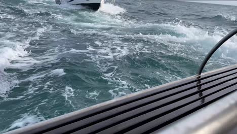 view of a ship pulling a boat in choppy sea from the stern