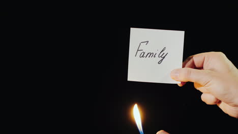 hand holds burning paper with inscription family