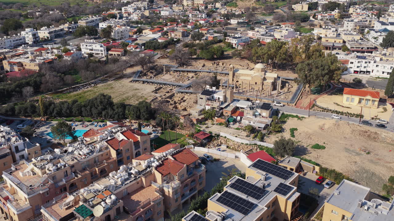 Vista aerea con drone che mostra rovine archeologiche accanto a edifici moderni a Pafo, Cipro