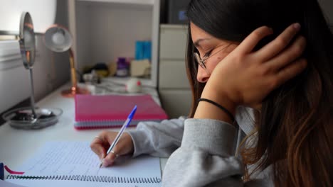 mujer joven centrada en escribir en un cuaderno en un escritorio en el entorno del hogar