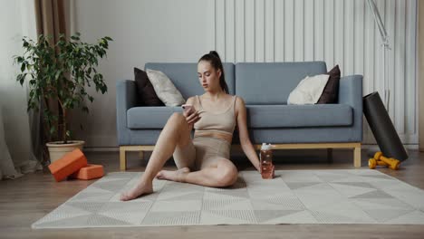 woman on a yoga mat, using her phone