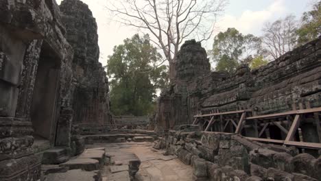 walking through a richely decorated but broken down temple in angkor wat, cambodia