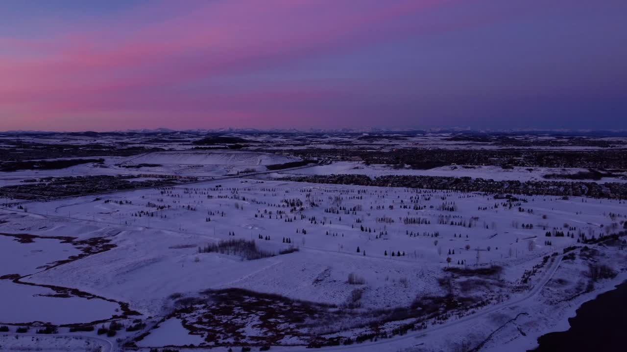 volar un dron en calgary durante un impresionante amanecer de invierno rosa y montañas en el fondo