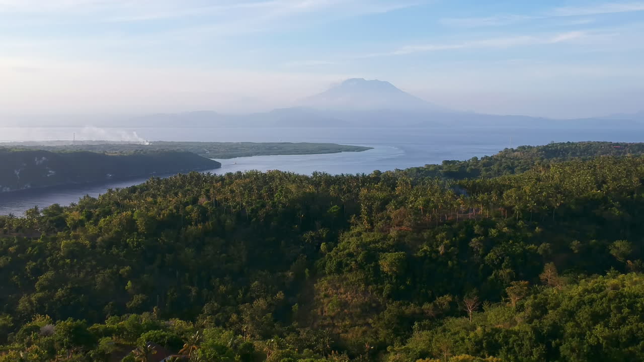 Drone Shot, Aerial view of a tropical forest, the sea and the vulcano Agung in the background.