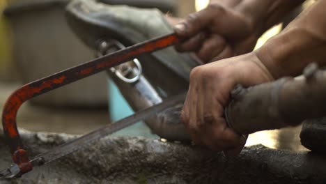 a man cutting bike silencer pipe with hacksaw