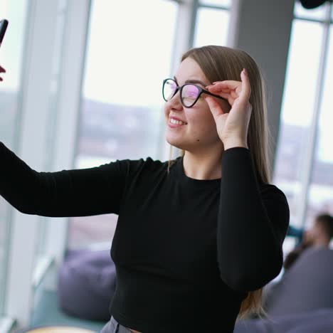 female freelancer in formal wear with eyeglasses taking selfie on cellphone