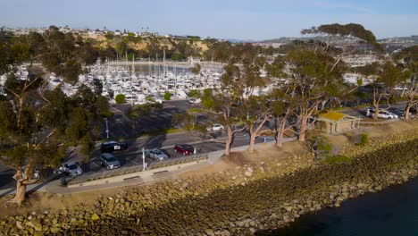 Aerial-pan-along-rock-reinforced-coastline-bordering-boat-harbor