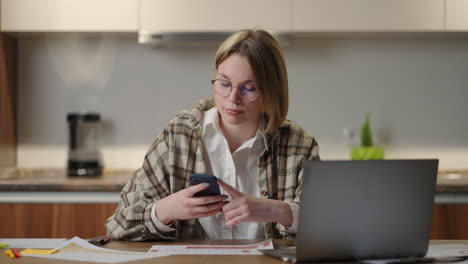 a happy smiling woman holds a mobile phone in her hands and laughs looking at the screen