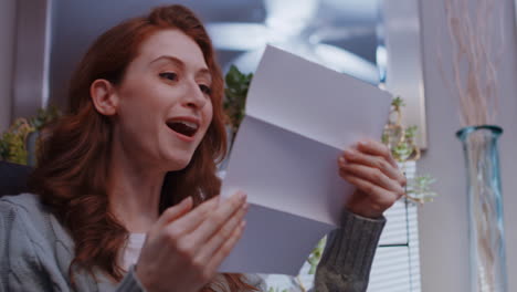 una joven mujer caucásica abre una carta y recibe grandes noticias con una pila de dinero en efectivo