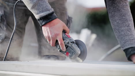 hand close-up of a man using angle grinder at a construction site outdoors