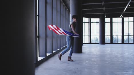 african american man dancing while holding american flag in empty parking garage