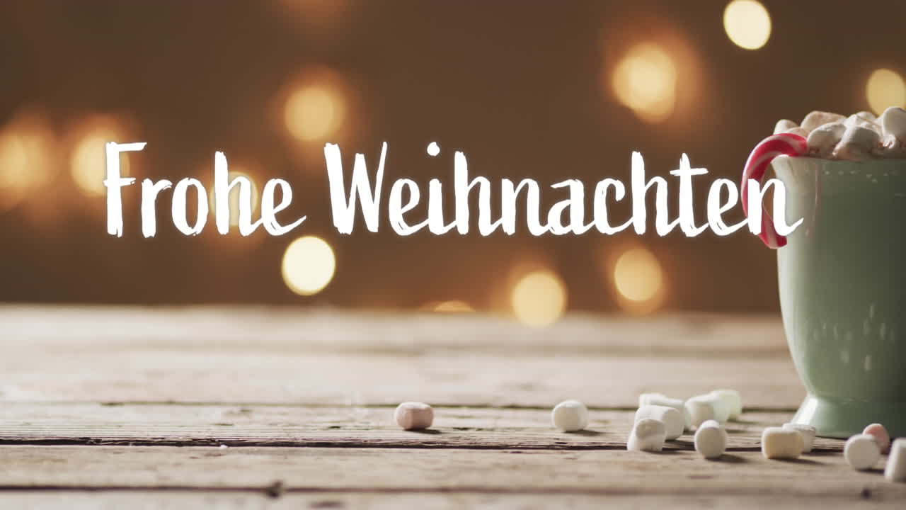 Text 'Frohe Weihnachten' mit Zuckerstange in weihnachtlicher heißer Schokolade mit Marshmallows und Bokeh-Lichtern