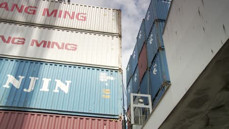 Low-angle-shot-of-a-towering-wall-formed-by-stacked-blue-and-white-containers,-under-a-clear-sky