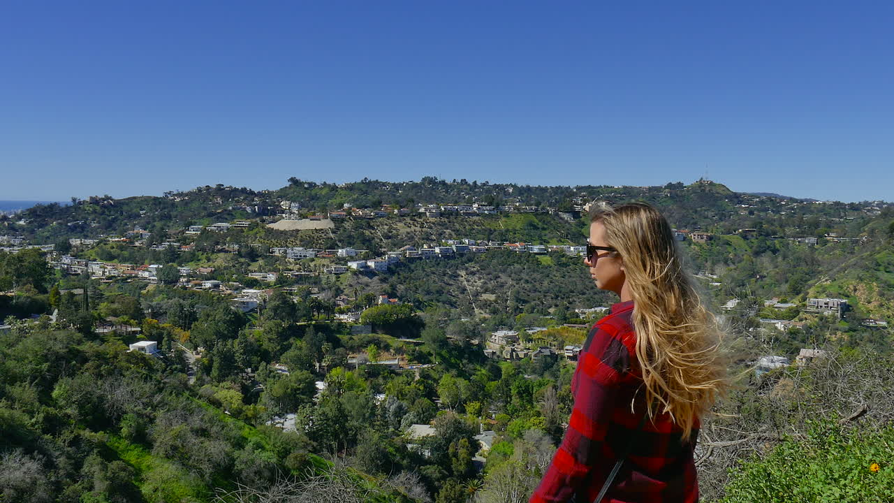 Young girl with flowing long brown hair, looks out over a valley in Los Angeles California