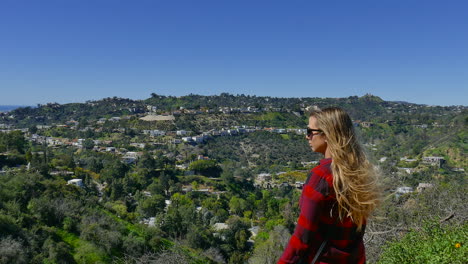 young girl with flowing long brown hair, looks out over a valley in los angeles california