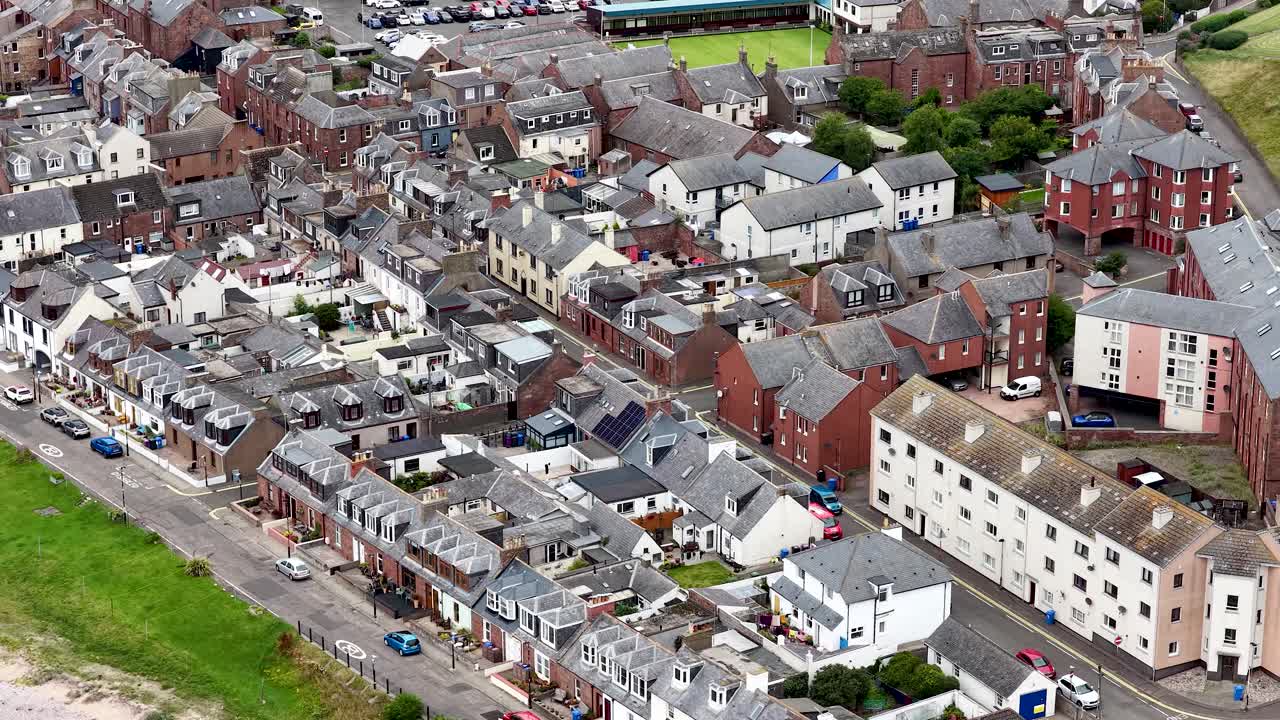 Aerial camera glides over Dundee’s seaside residential area, revealing rooftops, streets, and beachfront