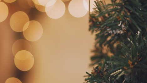 mano de mujer decorando el árbol de navidad con luces navideñas.