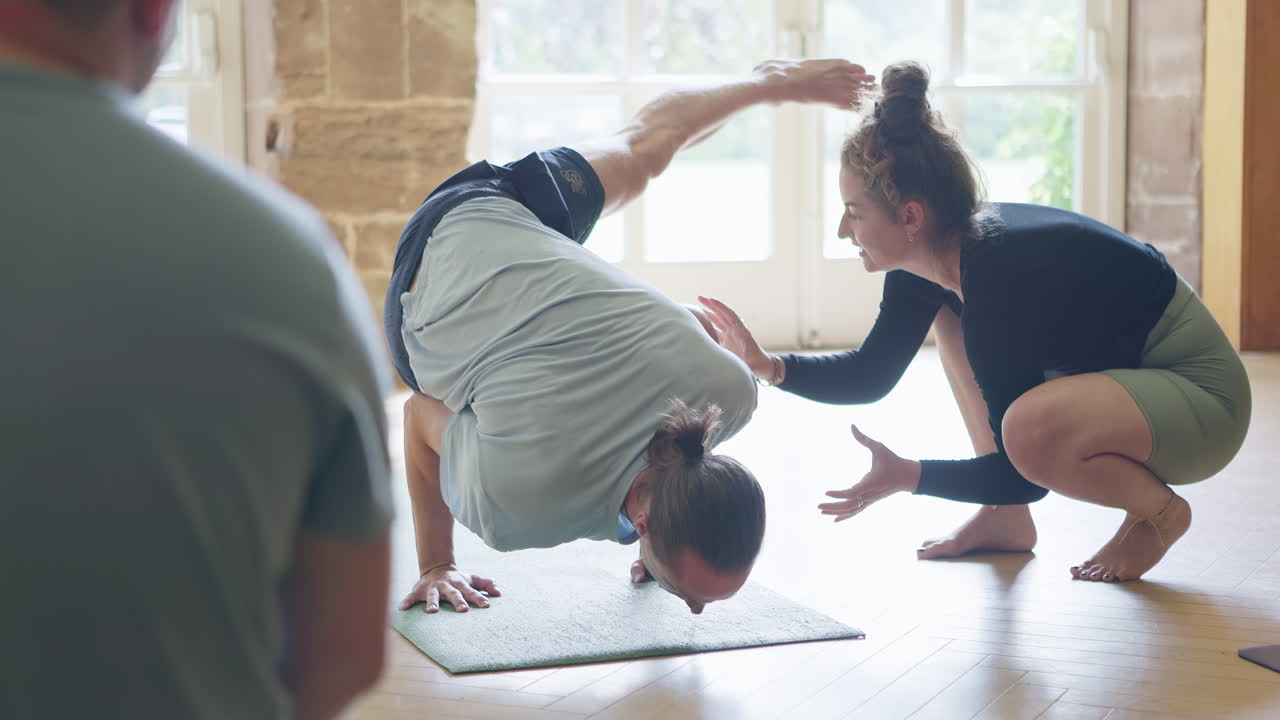 Yoga class with instructor assisting a student in a pose
