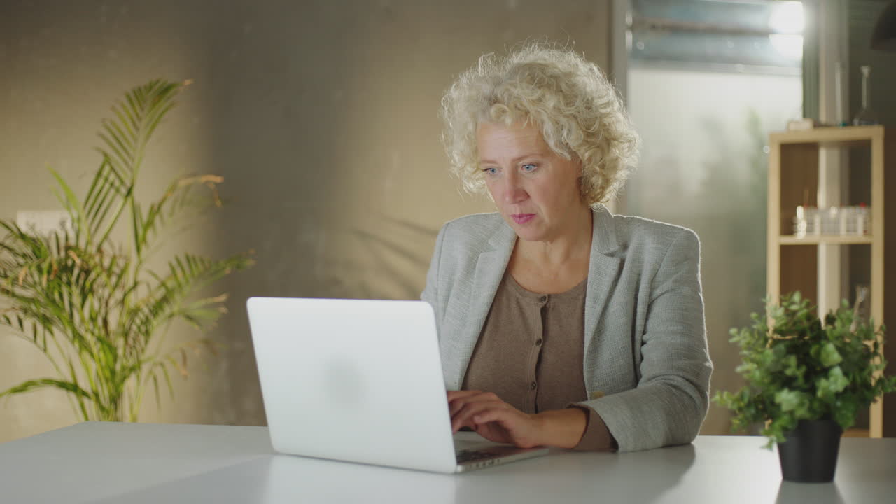 Donna di mezza età che lavora al laptop in ufficio.