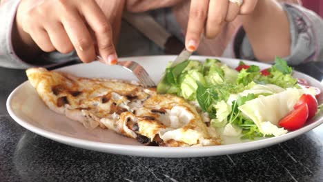 woman eating a delicious mushroom omelette with a side salad