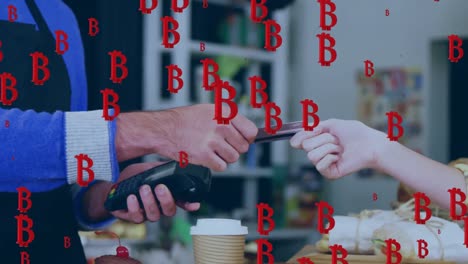animation of falling bitcoin sings over people using payment terminal