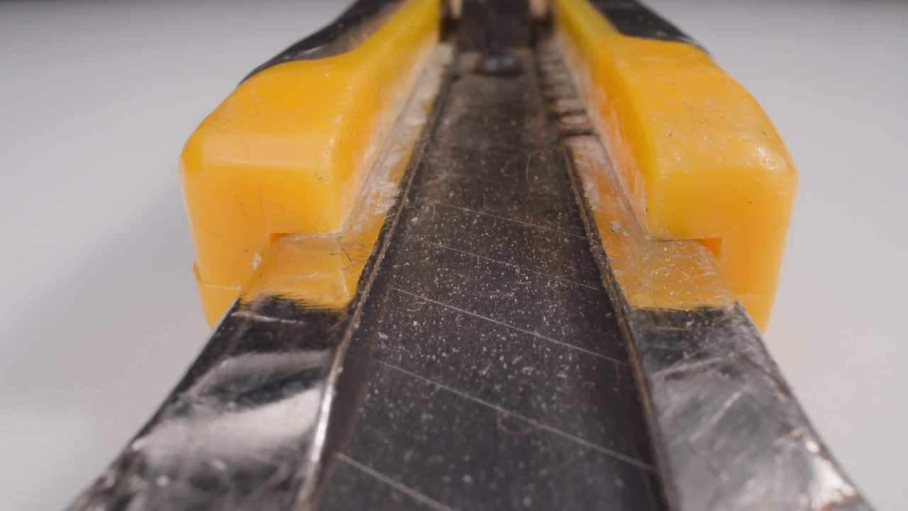 a lo largo del cortador de caja de movimiento con cuchilla abierta en la mesa blanca