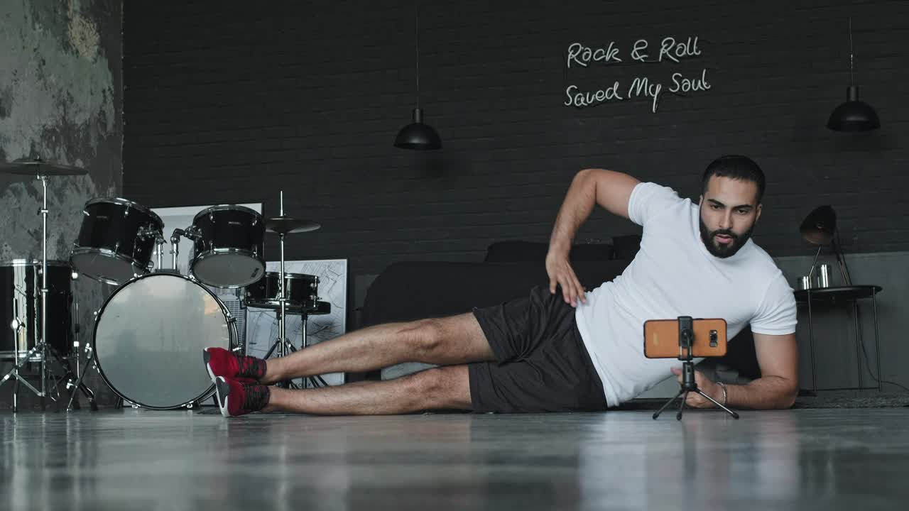 joven haciendo ejercicios en el estudio de música y lo dispara en el teléfono.